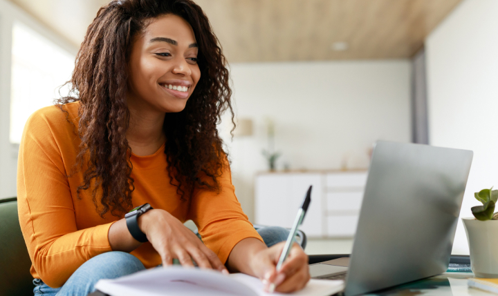 University of San Diego PCE | WordPress & Destiny One Website Integration 2 a female student with textured brown hair wearing an orange long sleeve shirt holds a pen while looking at a laptop screen